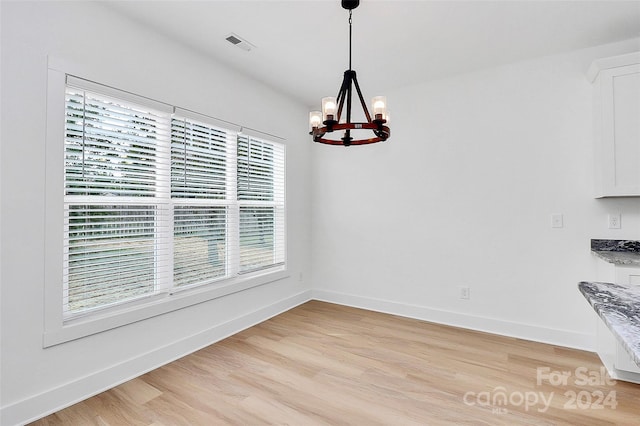 unfurnished dining area with light hardwood / wood-style flooring and an inviting chandelier