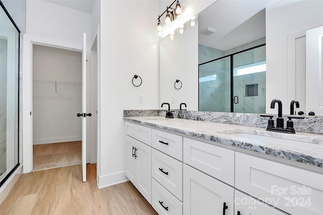 bathroom with hardwood / wood-style floors, vanity, and a shower with shower door