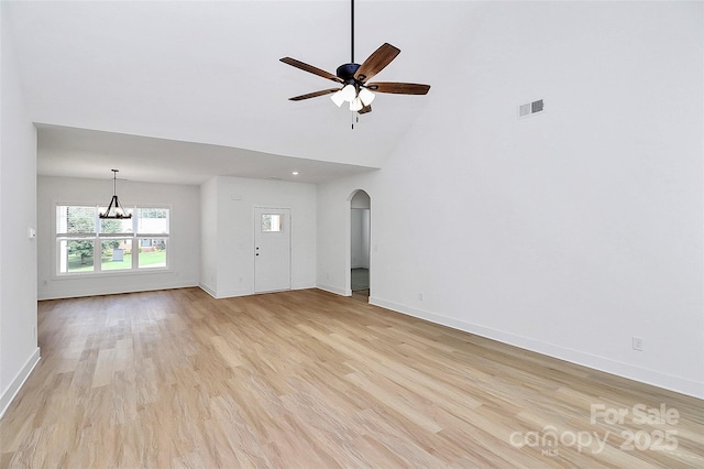 unfurnished living room featuring arched walkways, ceiling fan with notable chandelier, visible vents, and light wood-style floors