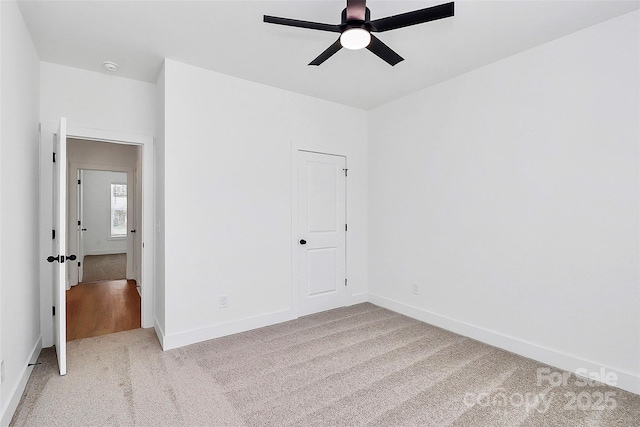 unfurnished bedroom featuring light carpet, baseboards, and a ceiling fan