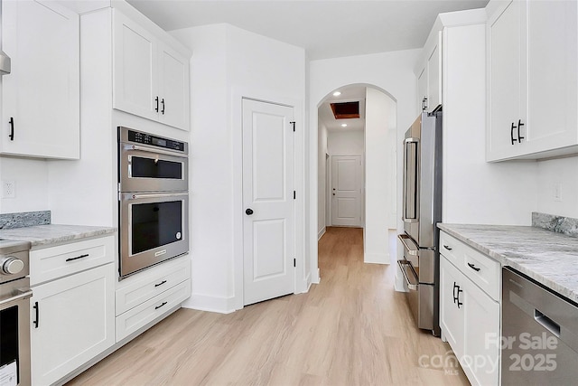 kitchen with light wood-style flooring, appliances with stainless steel finishes, and white cabinets