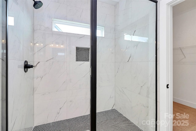 bathroom with a spacious closet and a marble finish shower