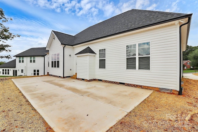 rear view of property with a shingled roof, crawl space, and a patio area