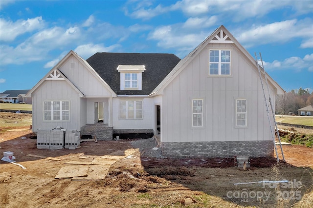 view of front of property featuring a shingled roof, brick siding, and board and batten siding