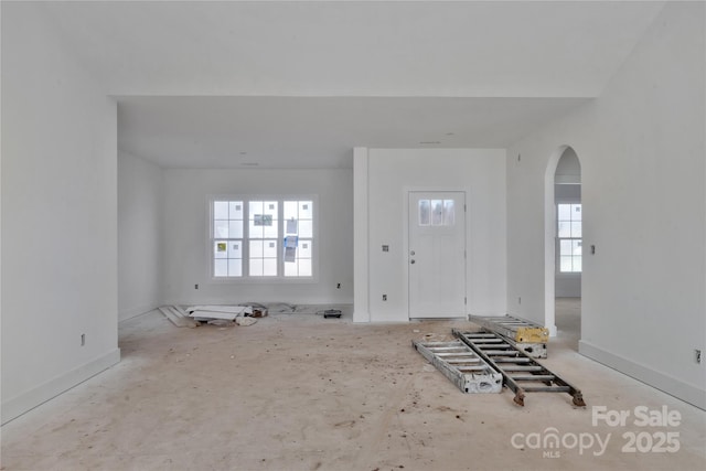 foyer featuring arched walkways and baseboards