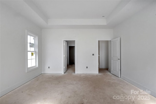 unfurnished bedroom with a raised ceiling and baseboards