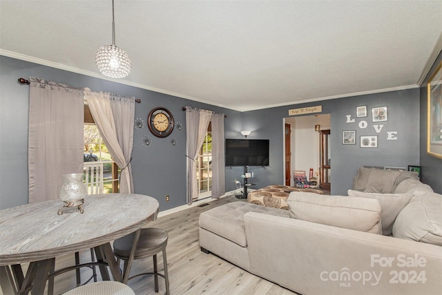 living room with crown molding, a chandelier, and light wood-type flooring