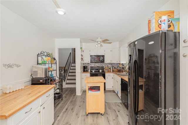 kitchen featuring black appliances, butcher block countertops, backsplash, white cabinetry, and light hardwood / wood-style floors