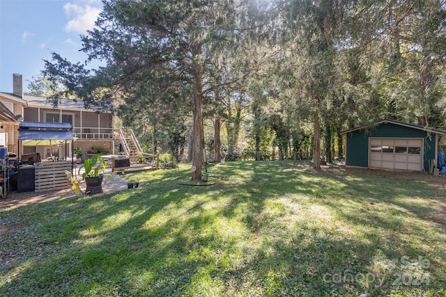 view of yard featuring a garage, a deck, and an outbuilding