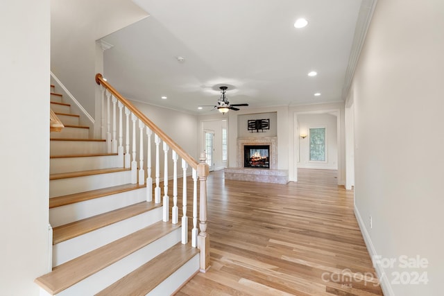 staircase with ceiling fan, crown molding, and hardwood / wood-style floors