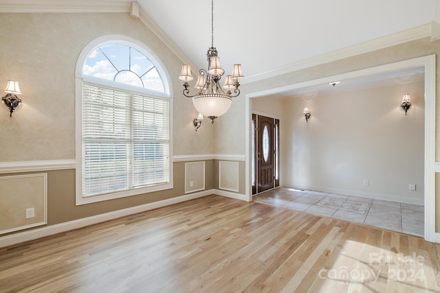 empty room with ornamental molding, light wood-type flooring, vaulted ceiling, and a notable chandelier