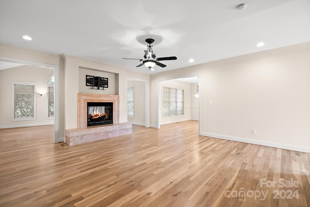 unfurnished living room featuring light hardwood / wood-style flooring, ceiling fan, a tile fireplace, and crown molding