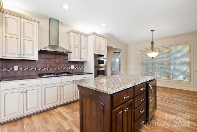 kitchen featuring backsplash, wall chimney exhaust hood, stainless steel appliances, light wood-type flooring, and beverage cooler