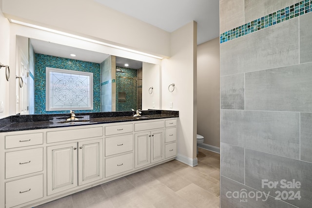 bathroom with a tile shower, vanity, and toilet