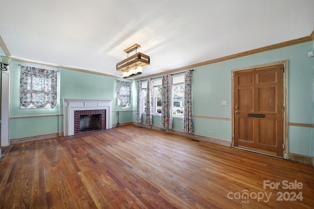 unfurnished living room featuring crown molding, hardwood / wood-style floors, and a brick fireplace