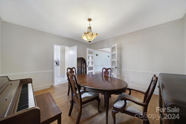 dining space with crown molding, light hardwood / wood-style flooring, and an inviting chandelier