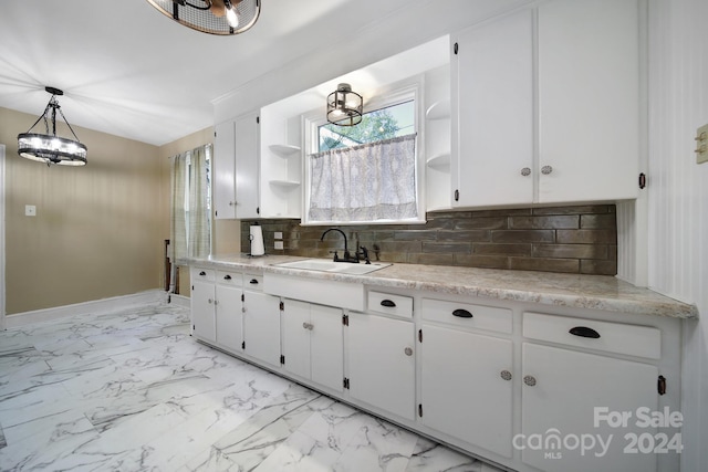 kitchen featuring decorative backsplash, white cabinetry, hanging light fixtures, and sink