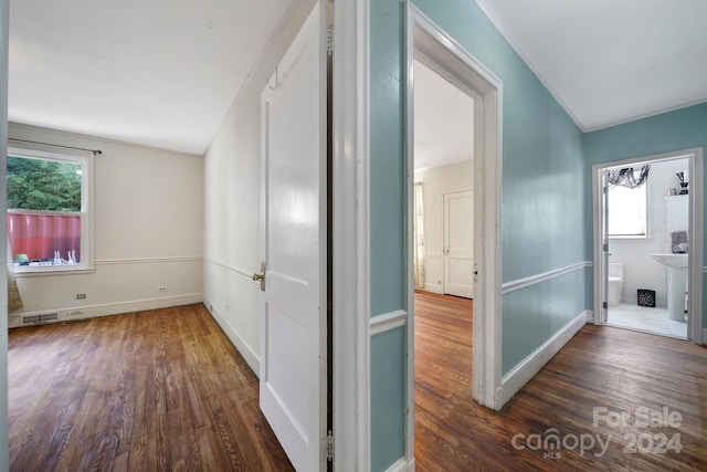 hall featuring plenty of natural light, ornamental molding, and dark wood-type flooring