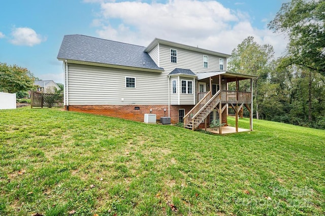 back of property with a lawn, central air condition unit, and a wooden deck