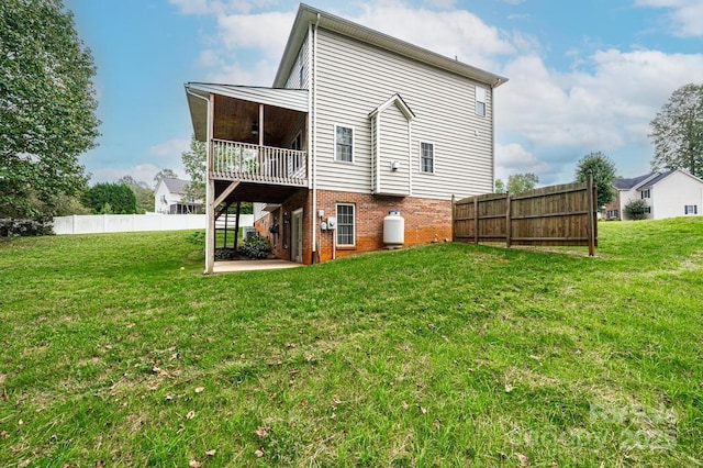 back of house featuring a lawn, a wooden deck, and a patio