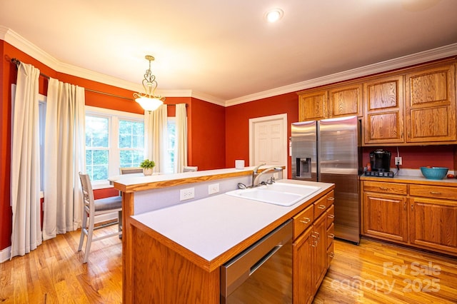 kitchen with sink, hanging light fixtures, crown molding, a kitchen island with sink, and appliances with stainless steel finishes