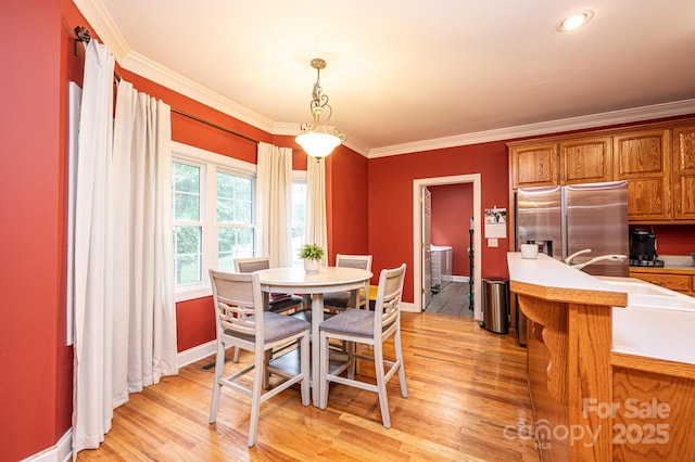 dining space featuring crown molding and light hardwood / wood-style flooring