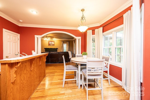 dining space featuring ceiling fan, light hardwood / wood-style floors, ornamental molding, and ornate columns