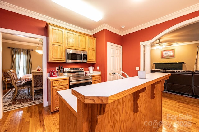 kitchen with a kitchen island, light wood-type flooring, crown molding, and appliances with stainless steel finishes