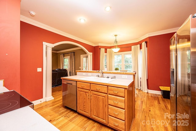 kitchen featuring stainless steel dishwasher, crown molding, sink, light hardwood / wood-style flooring, and hanging light fixtures