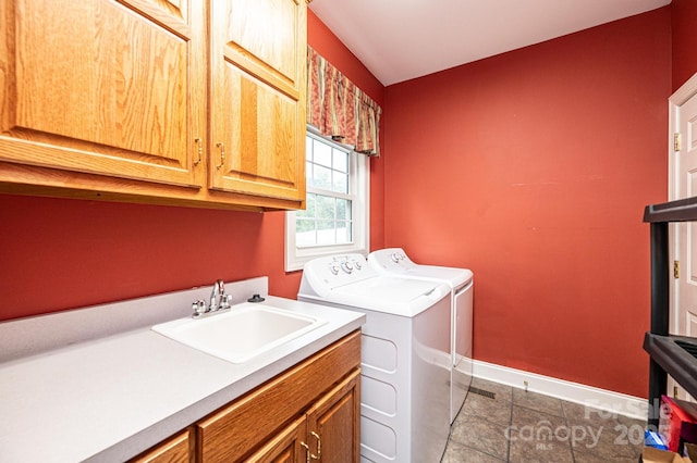 washroom with washer and clothes dryer, sink, cabinets, and dark tile patterned flooring