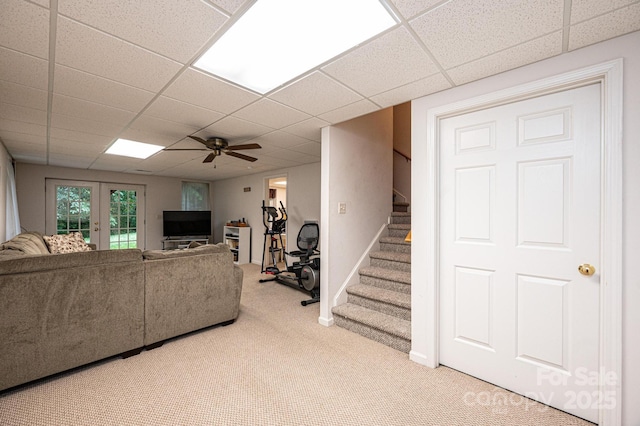 carpeted living room featuring ceiling fan, a drop ceiling, and french doors