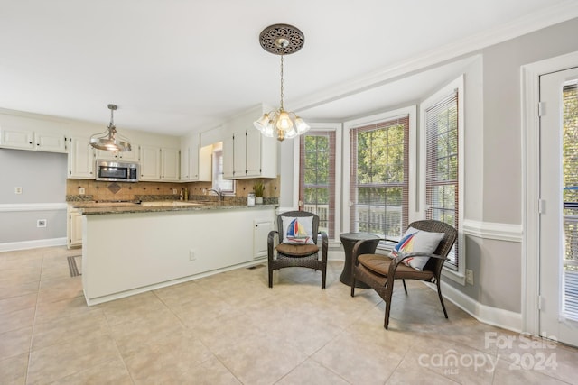 kitchen featuring kitchen peninsula, light tile patterned floors, backsplash, white cabinetry, and light stone countertops