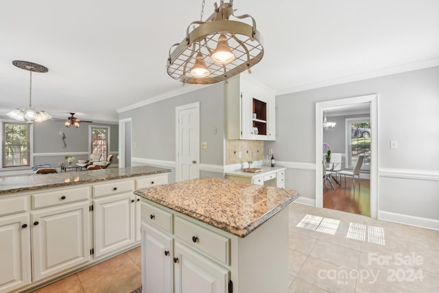 kitchen featuring ornamental molding, a center island, pendant lighting, and plenty of natural light