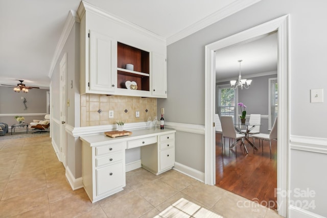 kitchen with backsplash, light tile patterned floors, ornamental molding, ceiling fan with notable chandelier, and decorative light fixtures