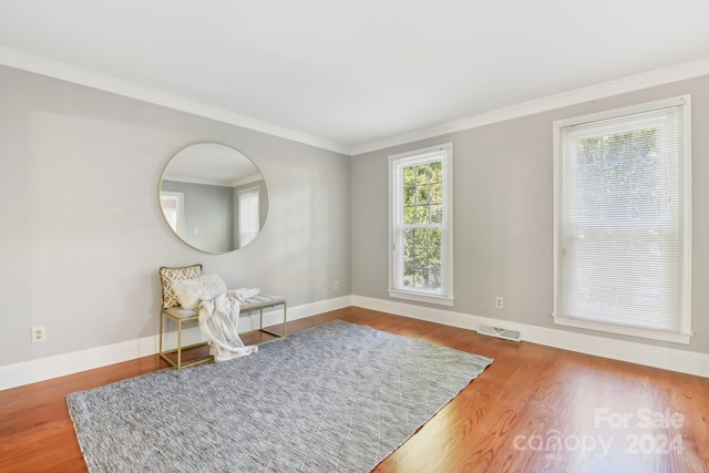 living area with ornamental molding and hardwood / wood-style flooring