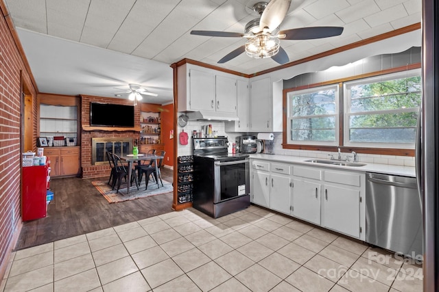 kitchen featuring sink, a brick fireplace, light hardwood / wood-style flooring, white cabinetry, and stainless steel appliances