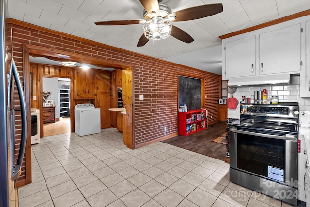 kitchen with light tile patterned flooring, electric stove, brick wall, white cabinets, and washer / dryer