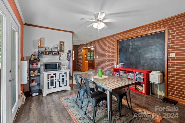 dining area with ornamental molding, dark hardwood / wood-style floors, ceiling fan, and brick wall