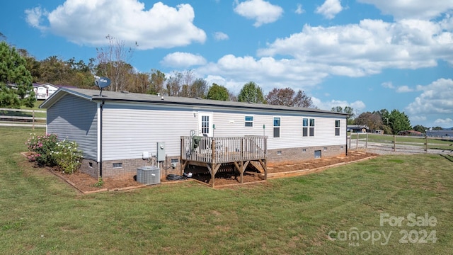 rear view of house with a wooden deck, cooling unit, and a lawn