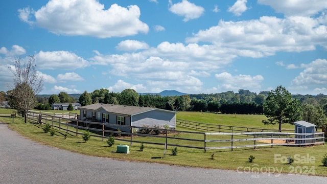 view of front facade with central AC, a rural view, a front yard, and a mountain view