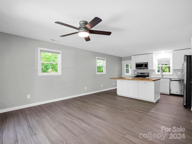 kitchen featuring white cabinetry, stainless steel appliances, wooden counters, light hardwood / wood-style flooring, and a wealth of natural light