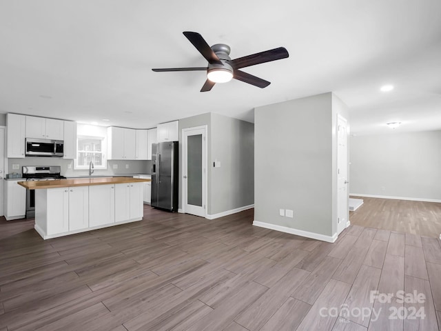 kitchen with white cabinets, appliances with stainless steel finishes, light wood-type flooring, and wooden counters