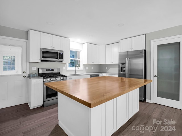 kitchen featuring a center island, wood counters, dark wood-type flooring, sink, and appliances with stainless steel finishes