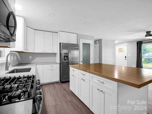 kitchen featuring a center island, wood counters, stainless steel appliances, and white cabinets