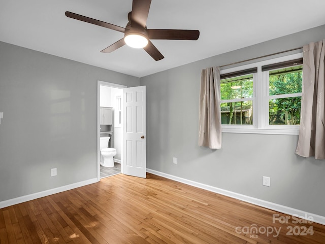 unfurnished bedroom featuring ensuite bath, ceiling fan, and hardwood / wood-style flooring