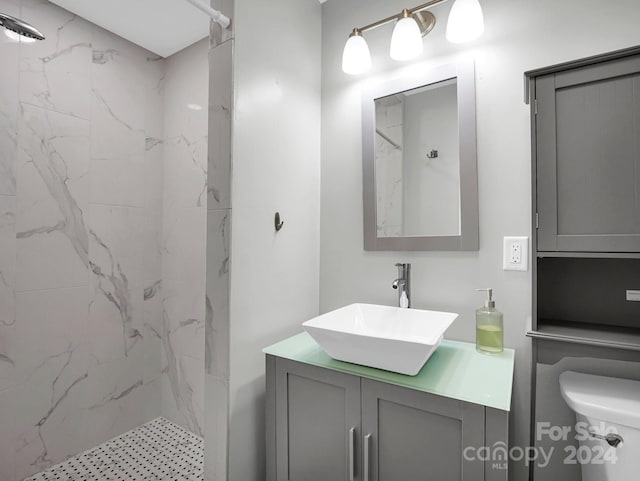 bathroom with tiled shower, vanity, and toilet