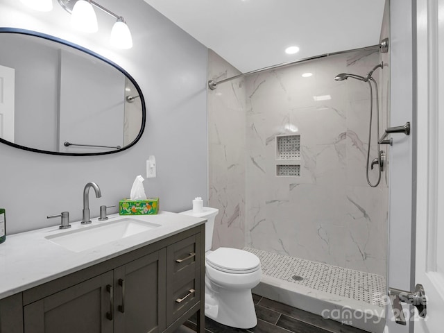 bathroom featuring tiled shower, vanity, and toilet