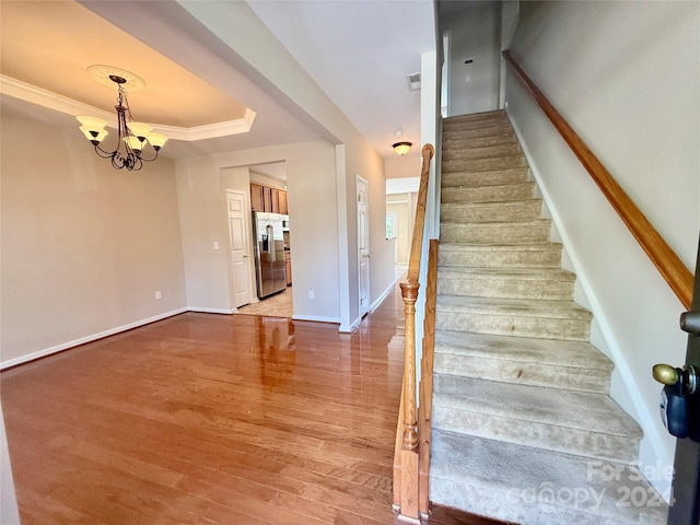 stairway featuring an inviting chandelier, crown molding, and hardwood / wood-style floors