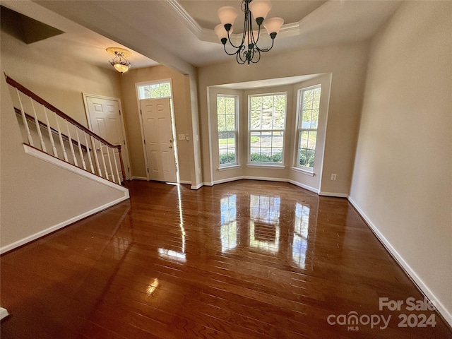 entryway featuring a notable chandelier, a raised ceiling, dark hardwood / wood-style floors, and plenty of natural light