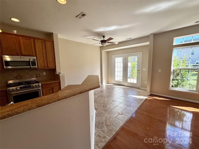 kitchen featuring appliances with stainless steel finishes, decorative backsplash, light wood-type flooring, and ceiling fan